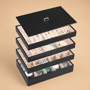 May include: A black, five-tier stackable jewelry organizer box with a removable lid. The interior features beige velvet lining with various compartments for necklaces, rings, and watches. The top tray holds necklaces, while lower trays contain dividers for smaller items and wristwatches.