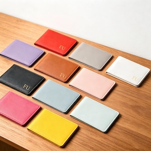 May include: A collection of eleven rectangular card holders in various solid colors including red, lavender, black, brown, gray, white, pink, light blue, hot pink, yellow, and mint green, each featuring the gold embossed letters FU on the front.