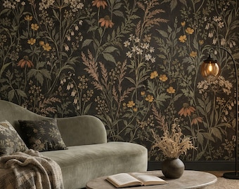 May include: A sage green velvet sofa with a textured throw blanket and a dark floral patterned pillow. An oval stone coffee table holds an open book and a vase of dried grasses. A black floor lamp stands beside the sofa against dark wallpaper.