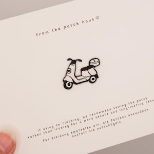 May include: A small black and white embroidered scooter patch centered on a white card. The card features the text from the patch haus with a heart symbol and instructions recommending sewing the patch onto clothing for a secure result.