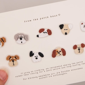 Könnte beinhalten: Ein Set aus neun kleinen gestickten Hunde-Aufnähern in verschiedenen Rassen und Farben, angeordnet auf einer weißen Karte mit dem Text from the patch haus und Anweisungen zum Annähen der Aufnäher an Kleidung für ein dauerhaftes Ergebnis.