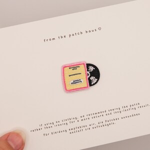 Puede incluir: Un parche bordado que muestra una funda de disco cuadrada de color amarillo con un borde rosa y un disco de vinilo negro que sobresale parcialmente por el lado. El parche está sujeto a una tarjeta blanca con el texto from the patch haus e instrucciones.