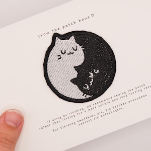 Peut inclure: Un écusson brodé circulaire présentant un motif yin-yang composé d'un chat blanc et d'un chat noir. L'écusson est fixé sur une carte blanche avec le texte from the patch haus et des instructions d'application en anglais et en allemand.