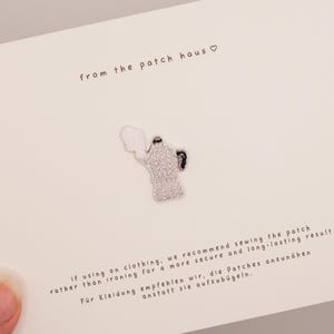 May include: An embroidered patch shaped like a moka pot coffee maker with white and black thread details, centered on a white card with the text from the patch haus and instructions for sewing the patch onto clothing for a secure result.