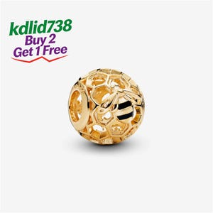 Può includere: Un ciondolo sferico color oro con un motivo a nido d'ape traforato e una piccola ape con strisce di smalto nero sul corpo. Il testo kdlid738 Buy 2 Get 1 Free è visibile nell'angolo in alto a sinistra, presentato in verde e viola.
