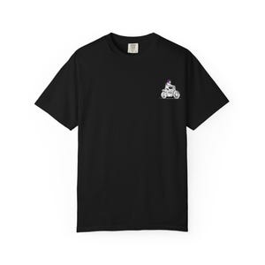 Peut inclure: Un t-shirt noir à manches courtes avec un petit motif sur la poitrine gauche. Le motif représente une personne portant un casque violet sur une moto blanche. Le t-shirt présente une encolure ronde classique et un ourlet droit au bas.