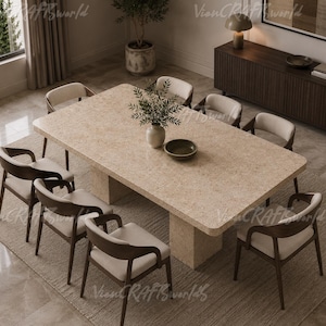 Puede incluir: Una mesa de comedor rectangular con una superficie beige moteada efecto piedra y una base de pedestal gruesa, rodeada por ocho sillas con marcos de madera oscura y asientos tapizados en beige claro, sobre una alfombra texturizada.
