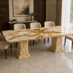 Puede incluir: Una mesa de comedor rectangular con tablero de mármol pulido en tonos ámbar y blanco con vetas doradas, sostenida por dos bases de pedestal estriadas de mármol a juego, acompañada de seis sillas beige tapizadas con patas oscuras.