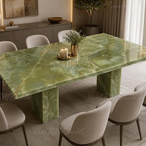 Puede incluir: Una mesa de comedor rectangular con un tablero de piedra ónix verde pulido con vetas naturales y dos bases de pedestal de piedra maciza a juego, rodeada por seis sillas tapizadas en tela beige claro con patas de madera marrón oscuro.