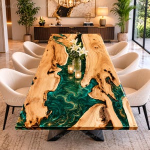 May include: A rectangular dining table featuring two natural live-edge wood slabs separated by a swirling, translucent emerald green resin river inlay. The table is supported by a dark metal base and surrounded by six cream-colored upholstered chairs.