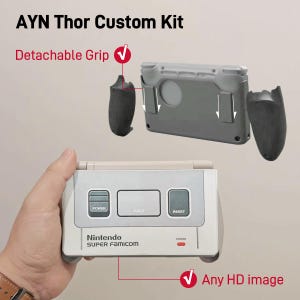 Op de afbeelding: AYN Thor Custom Kit met een handheld gameconsolebehuizing in de stijl van een Nintendo Super Famicom met power-, eject- en resetknoppen. De set bevat twee zwarte afneembare grepen die aan de zijkanten van de grijze consolebehuizing schuiven.