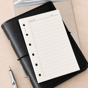 May include: A cream-colored paper to-do list insert with six punched holes along the left side. The page features the printed text To Do List and Date at the top, followed by a series of horizontal lines with small square checkboxes for tasks.