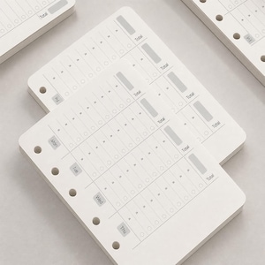 May include: A stack of white planner refill pages with pre-printed daily tracking grids. Each page features columns for Mon, Tue, Wed, Thu, and Fri, with rows of circles and arrows for tasks, plus a gray box labeled Total at the end of each row.