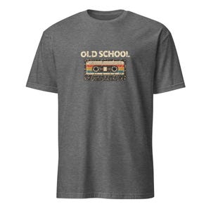Könnte beinhalten: Ein dunkelgrau meliertes Kurzarm-T-Shirt mit einem Grafikdruck einer Kassette in abgenutzter Optik. Über der Kassette ist der Text OLD SCHOOL in einer fetten, cremeweißen serifenlosen Schrift gedruckt. Das Kassettendesign enthält horizontale Streifen in den Farben Rot, Gelb und Blau.