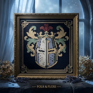 May include: A framed cross-stitch embroidery featuring a knight's helmet crest in white, blue, and gold on a dark navy background, surrounded by a decorative border. The text FOLK & FLOSS is printed in gold at the bottom of the frame.