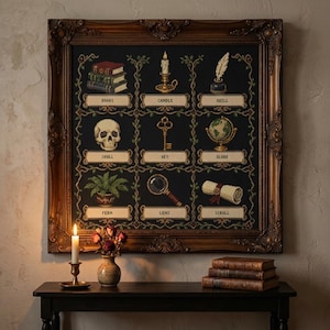 May include: A framed cross-stitch sampler on a black background featuring a grid of nine items: books, candle, quill, skull, key, globe, fern, lens, and scroll. Each item is labelled with its name in a rectangular box. The frame is ornate and dark brown.