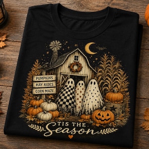 May include: A black t-shirt featuring a graphic of a barn, three ghosts, pumpkins, and a sign that reads PUMPKINS, HAY RIDES, CORN MAZE. Below the scene, the text reads TIS THE SEASON with a small heart. The design includes a crescent moon and stars.