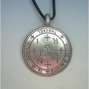 May include: Silver pendant necklace with a circular design featuring the words "THAVVEL ISCHIROS EL ELOHIM ELOHA" and a symbol in the centre. The necklace is on a black cord.