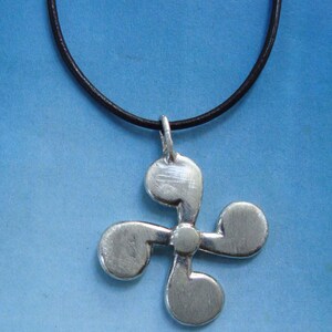 May include: A silver propeller pendant necklace on a black leather cord. The pendant is a four-bladed propeller with a smooth, polished finish.