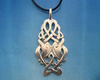 May include: Silver pendant necklace with a Celtic knot design featuring two intertwined birds. The pendant is attached to a black cord.