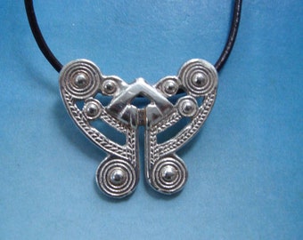 May include: A silver pendant necklace with a Celtic knot design in the shape of a butterfly. The pendant is on a black cord.