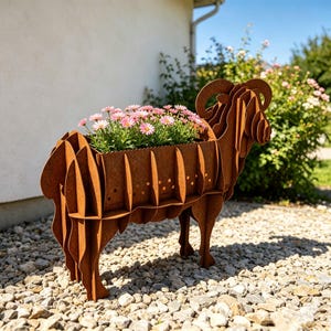 Puede incluir: Una maceta de metal color óxido con forma de carnero y cuernos curvados. El cuerpo del carnero sirve como recipiente para un grupo de pequeñas flores rosas con centros amarillos. La estructura está compuesta por paneles metálicos planos.