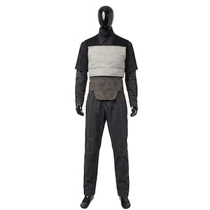 May include: A dark grey long-sleeved shirt and matching trousers set featuring a light grey quilted chest panel and a dark brown waist belt. The ensemble is displayed on a black mannequin, showcasing a structured design with visible stitching details on the trousers and sleeves.