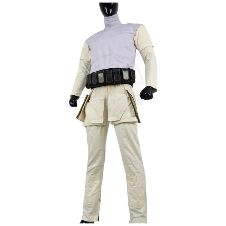 May include: A costume ensemble featuring a light lavender mock-neck top with cream-colored sleeves, paired with cream-colored trousers that have large side pockets. A black utility belt with multiple rectangular pouches is worn around the waist.