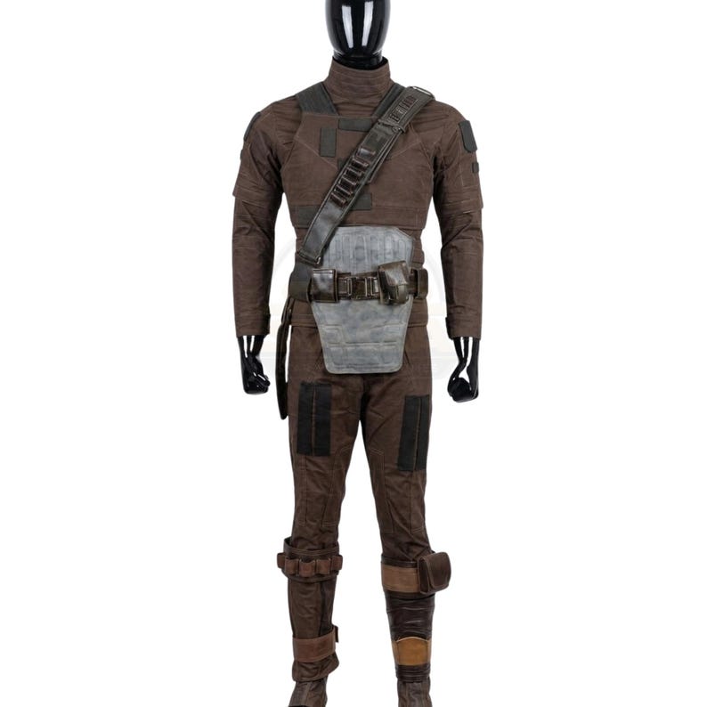 K&ouml;nnte beinhalten: Ein braunes taktisches Kost&uuml;mset bestehend aus einem lang&auml;rmeligen Oberteil und einer passenden Hose. Das Outfit umfasst einen dunkelbraunen Schulterriemen, eine graue Bauchpanzerplatte, einen G&uuml;rtel mit Taschen und braune Beinsch&uuml;tzer.