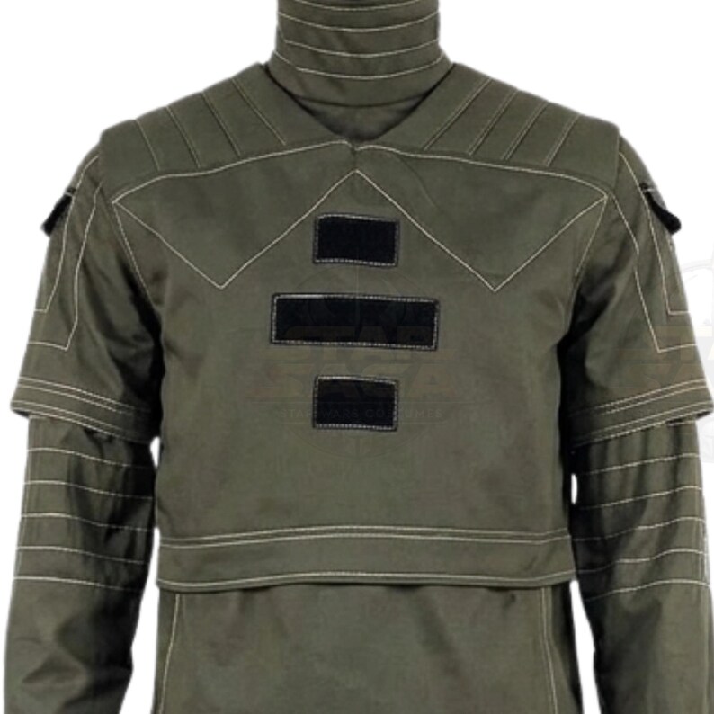May include: An olive green long-sleeve tactical shirt featuring a high mock neck collar, reinforced shoulder panels with visible white stitching, and three rectangular black hook-and-loop patches centered on the chest area.