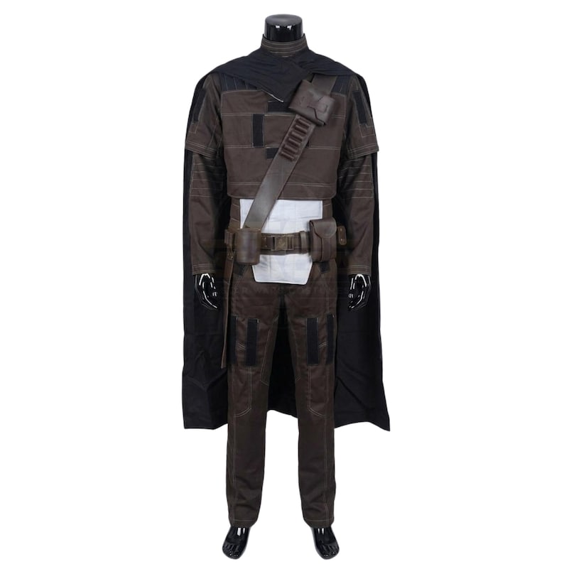 Peut inclure: Un ensemble de costume marron fonc&eacute; comprenant une longue cape noire, un haut marron avec des d&eacute;tails surpiqu&eacute;s et un pantalon marron assorti. La tenue inclut une ceinture utilitaire marron avec des poches et une bandouli&egrave;re diagonale.