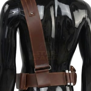 May include: A brown leather belt and shoulder strap set featuring a wide waist belt with integrated pouches and a diagonal shoulder strap. The belt includes two silver-colored cylindrical canisters attached to the side and a metal buckle fastener.
