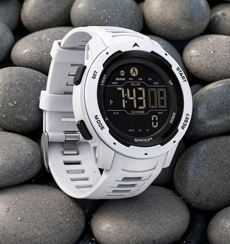 May include: A white digital sports watch with a black circular face and a silicone strap. The display shows the time 7:43, the text SAMOA, and various function labels including SET, LIGHT, MODE, START, RESET, UP, DOWN, ALM, CHIME, KM, KG, and MILE.