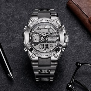 May include: A silver and black analog-digital sport watch with a metallic link band. The watch face features the text SPORT WATCH, LIGE, and WATER RESIST, with multiple sub-dials, a digital display, and silver hour markers on a dark gray background.