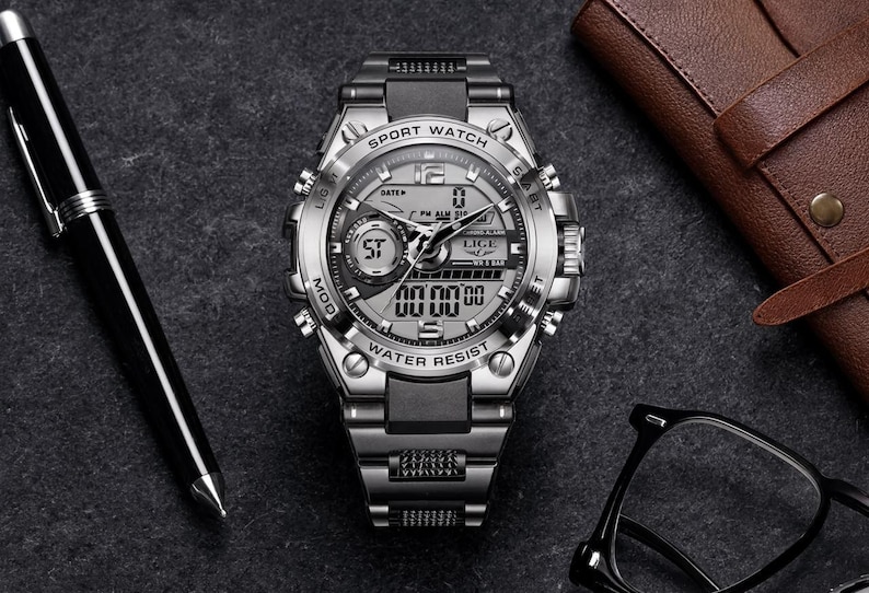 May include: A silver and black analog-digital sport watch with a metallic link band. The watch face features the text SPORT WATCH, LIGE, and WATER RESIST, with multiple sub-dials, a digital display, and silver hour markers on a dark gray background.