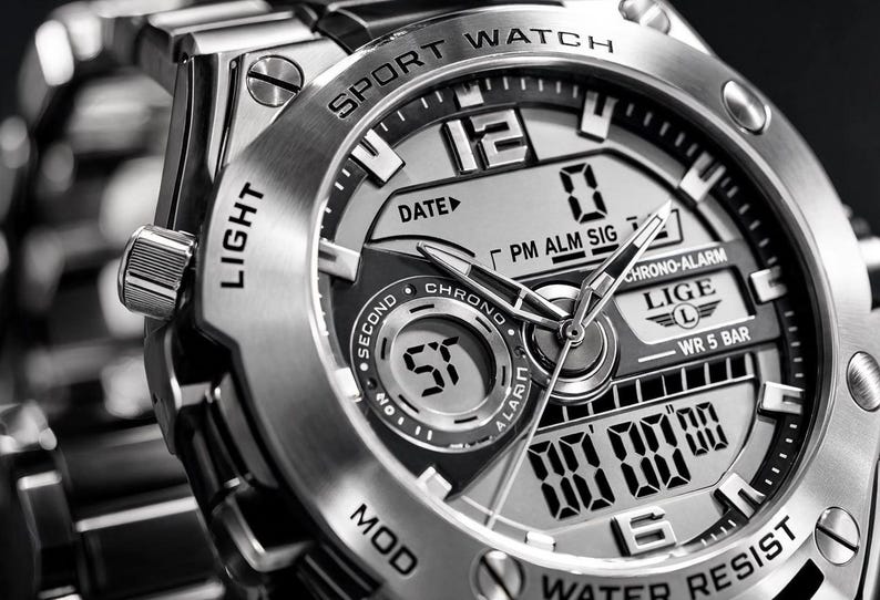 May include: A silver-toned analog-digital sport watch with a metallic link band. The watch face features the text LIGE, SPORT WATCH, WATER RESIST, DATE, CHRONO, and ALARM. It includes both physical hour and minute hands and a digital display screen.