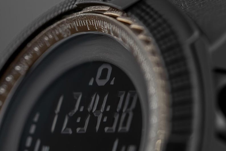 May include: A black digital watch with a textured bezel and a dark display screen showing the time 12:34:38 in a stylised font. The watch features a metallic bronze-toned inner ring with etched markings and a rugged, matte black casing.