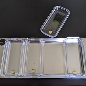 May include: A rectangular silver-toned metal tray featuring three integrated clear acrylic rectangular compartments and one separate clear acrylic rectangular tray. Each clear piece has a small circular gold-toned label with the text "INSERTO".