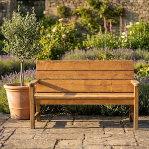Könnte beinhalten: Eine Gartenbank aus Holz mit natürlichem braunem Finish, bestehend aus einer Rückenlehne mit Latten, einer flachen Sitzfläche und zwei Armlehnen. Die Bank ist aus horizontalen Holzplanken mit sichtbarer Maserung gefertigt und steht auf vier Beinen.