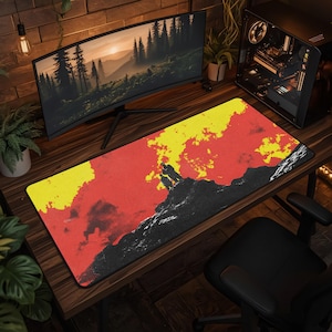Puede incluir: Una alfombrilla de escritorio rectangular con una ilustración gráfica de dos figuras sobre un pico de montaña oscuro y texturizado, frente a un fondo de formas abstractas rojas y amarillas, con un borde negro que rodea toda la superficie.