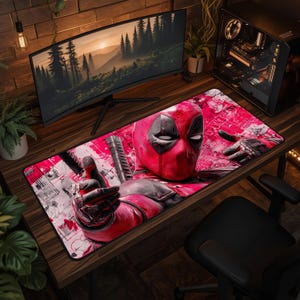 Può includere: Un tappetino da scrivania rettangolare con una vivace grafica rossa e nera del personaggio Deadpool. Il design include un primo piano del volto mascherato, una mano guantata protesa in avanti e l'elsa di una spada su uno sfondo in stile graffiti.