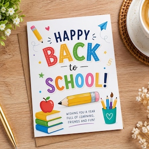 May include: A white greeting card with the text HAPPY BACK TO SCHOOL in colorful letters. The design features a red apple on a stack of books, a yellow pencil, a teal cup with pens, and small icons like a heart and paper plane. Text reads WISHING YOU A YEAR FULL OF LEARNING, FRIENDS AND FUN!
