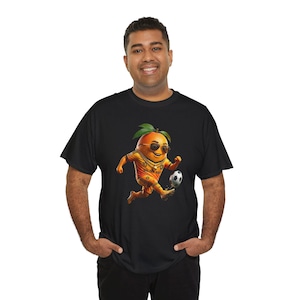 Peut inclure: Un t-shirt noir avec un motif représentant un personnage en forme d'orange portant des lunettes de soleil, une chaîne dorée et un maillot de football jaune avec le numéro 10 et le texte GOLDEN BOOT, frappant un ballon de football.