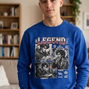 Peut inclure: Un sweat-shirt bleu roi à col rond avec une impression graphique portant le mot LEGEND en haut. Le design comprend trois illustrations en noir et blanc étiquetées ARTIST, VOICE et LEGACY, ainsi que le texte 90s CREATIVE, LIGHT SOUL et LOST UNITEE SOUL.