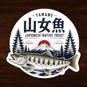 May include: A circular sticker featuring a detailed illustration of a Yamame Japanese native trout. The design includes a mountain, pine trees, a red sun, and the text YAMAME, 山女魚, and JAPANESE NATIVE TROUT in dark blue lettering.