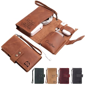 May include: A brown leather tech organizer with a wrist strap, featuring the engraved text "The Best Memories Are Made With You MERRY CHRISTMAS 2026" and "Christian". The organizer holds electronic accessories, and a closed version shows the name "DAVID".