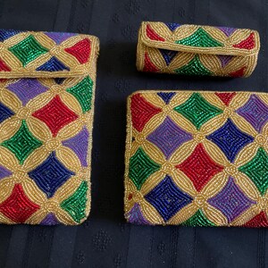 May include: A set of three accessories including a tall rectangular pouch, a small cylindrical case, and a wide rectangular clutch. Each item is covered in a repeating diamond pattern of gold, red, green, blue, and purple glass beads.