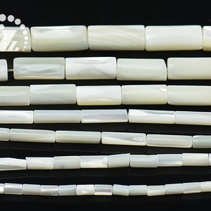 Può includere: Una collana di perle bianche di madreperla di diverse dimensioni. Le perle sono rettangolari e hanno una finitura liscia e lucida.