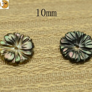 May include: Two 10mm black and iridescent mother of pearl flower shaped buttons with a hole in the center.