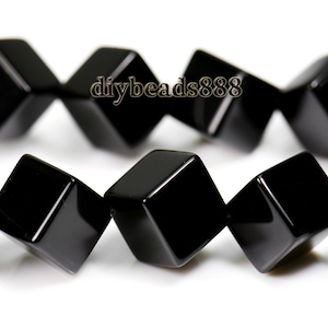 May include: A strand of black onyx beads, each bead is faceted and shaped like a cube. The beads are strung together in a staggered pattern, creating a unique and stylish look.